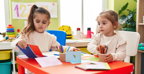 Fototapeta premium Two kids preschool students sitting on table drawing on paper at kindergarten