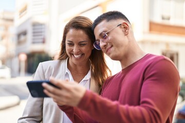 Man and woman mother and son smiling confident using smartphone at street