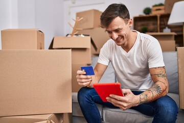 Young man using touchpad and credit card at new home