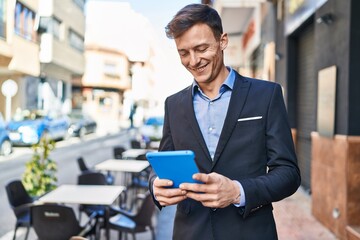 Young man business worker smiling confident using touchpad at coffee shop terrace