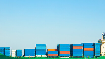 A large cargo container ship loaded with containers against the blue sky and empty space