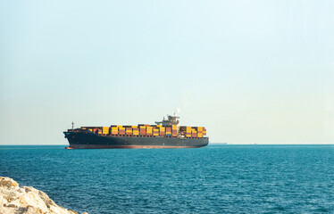 Large cargo container ship loaded with containers against the blue sky