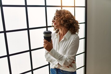 Mature hispanic woman working drinking a coffee at the office