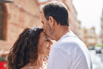 Man and woman couple hugging each other kissing at street