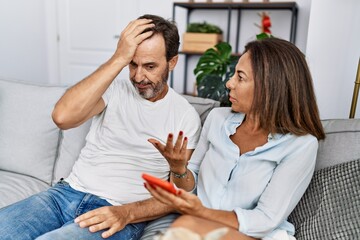 Middle age man and woman couple with problem for infidelity using smartphone at home