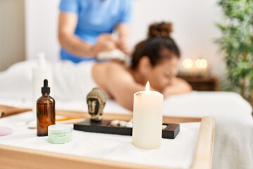 Middle age man and woman wearing therapist uniform having back massage session using thai bags at beauty center