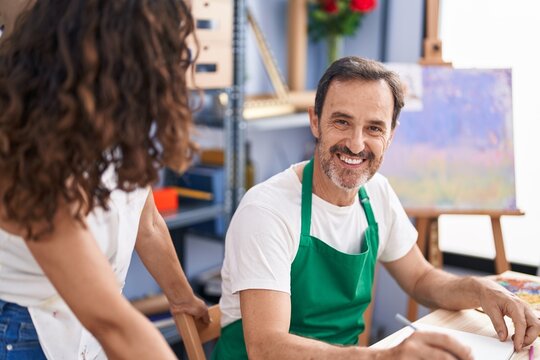 Man and woman artists smiling confident drawing on notebook at art studio