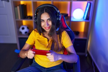 Young beautiful arab woman streamer playing video game using smartphone at gaming room