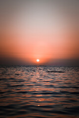 Obraz premium Vibrant sunset descending on the horizon, sea in golden colors, small waves gently touching the sands,
