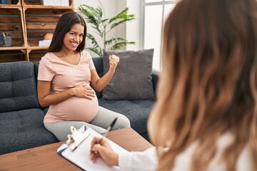 Young pregnant woman at therapy session very happy and excited doing winner gesture with arms...