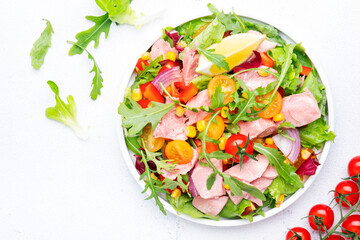 Tuna vegetables salad with colorful cherry tomatoes, red onion, sweet corn, paprika, lettuce, radicchio and arugula. White table background, top view