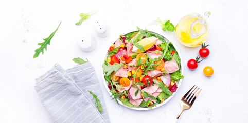 Tuna vegetables salad with colorful cherry tomatoes, red onion, sweet corn, paprika, lettuce, radicchio and arugula. White table background, top view