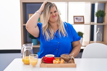 Caucasian plus size woman eating breakfast at home confuse and wonder about question. uncertain with doubt, thinking with hand on head. pensive concept.