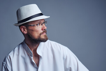 Confident serious middle age man in straw hat and eyeglasses looking at side