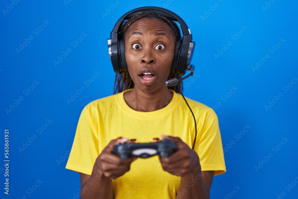 Canvas Prints African american woman playing video games afraid and shocked with surprise and amazed expression, fear and excited face.