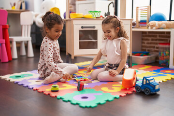 Naklejka premium Two kids playing xylophone sitting on floor at kindergarten