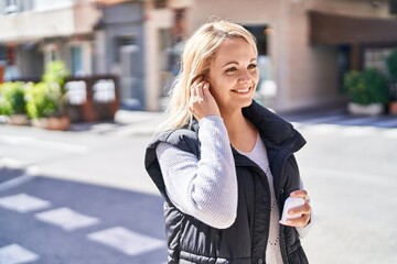 Plakat Young blonde woman listening to music at street