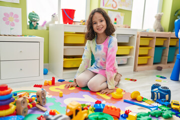 Fototapeta premium Adorable chinese girl smiling confident sitting on floor at kindergarten