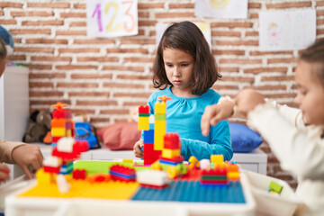 Two kids playing with construction blocks sitting on table at kindergarten