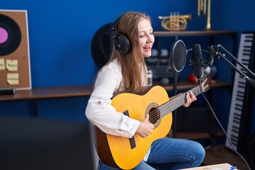 Young caucasian woman musician singing song playing classical guitar at music studio