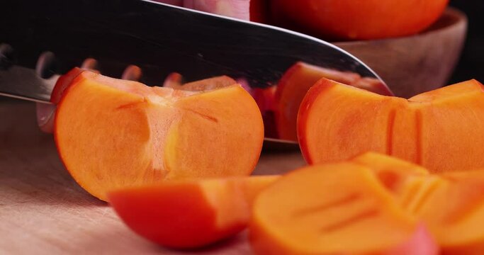 Cutting into pieces of ripe orange persimmon, cooking food using fresh persimmon, which is cut into pieces