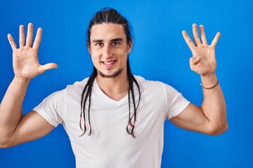 Hispanic man with long hair standing over blue background showing and pointing up with fingers...