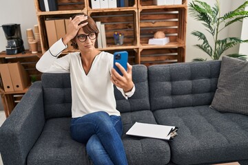 Obraz premium Brunette woman doing online session at consultation office stressed and frustrated with hand on head, surprised and angry face