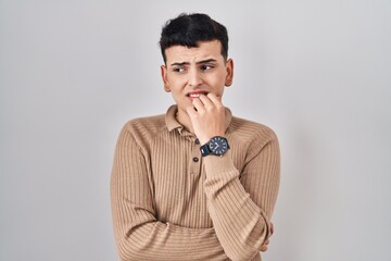 Non binary person standing over isolated background looking stressed and nervous with hands on...