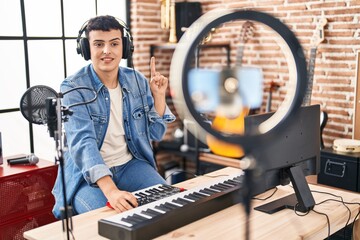 Non binary person doing online music tutorial smiling with an idea or question pointing finger with happy face, number one