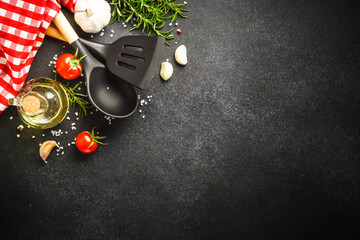 Food background on black. Herbs, spices and utensil for healthy cooking. Top view with copy space.