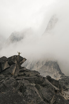 Man with outstretched arms standing on a rocky spire in Bugaboo Provincial Park, Radium, British Columbia, Canada.