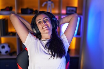 Young beautiful hispanic woman streamer smiling confident relaxed with hands on head at gaming room