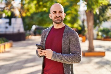 Fototapeta premium Young man smiling confident using smartphone at park