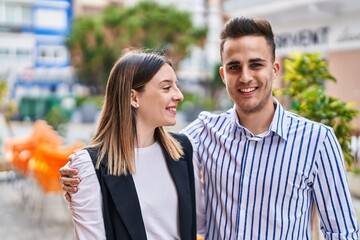 Naklejka premium Man and woman couple smiling confident hugging each other at street