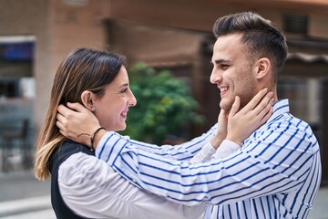 Naklejka premium Man and woman couple smiling confident hugging each other at street