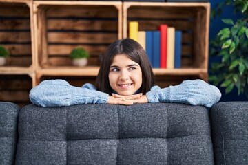 Young beautiful hispanic woman smiling confident leaning on sofa at home