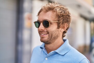 Young man smiling confident wearing sunglasses at street