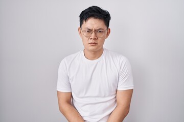 Young asian man standing over white background skeptic and nervous, frowning upset because of problem. negative person.