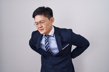 Young asian man wearing business suit and tie suffering of backache, touching back with hand, muscular pain