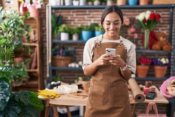 Young beautiful hispanic woman florist smiling confident using smartphone at florist