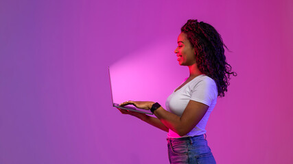 Smiling Black Woman Holding Laptop And Looking At Glowing Screen