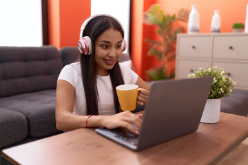 Young arab woman listening to music drinking coffee at home