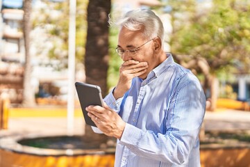 Senior man using touchpad with surprise expression at park