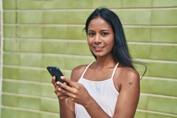 Young beautiful woman smiling confident using smartphone over isolated green background