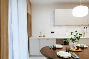 Obraz na płótnie Canvas stylish oak studio kitchen with a dark table and a light kitchen