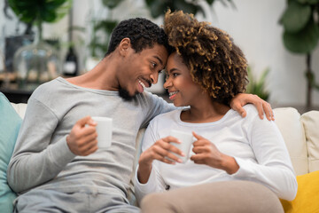 Portrait of loving black couple drinking coffee at home