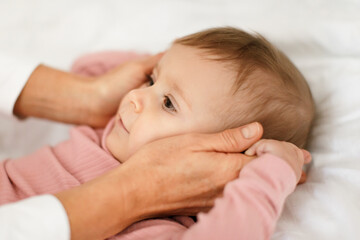 Mother and kid concept. Loving mom cuddling with her beautiful little baby girl at home, lying on bed, closeup