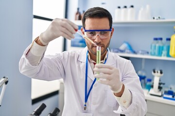 Young hispanic man scientist measuring liquid at laboratory