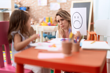 Teacher and toddler sitting on table having emotion therapy at kindergarten