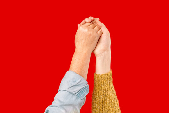 Close up of two female hands together on red background. Hands of caucasian female. 